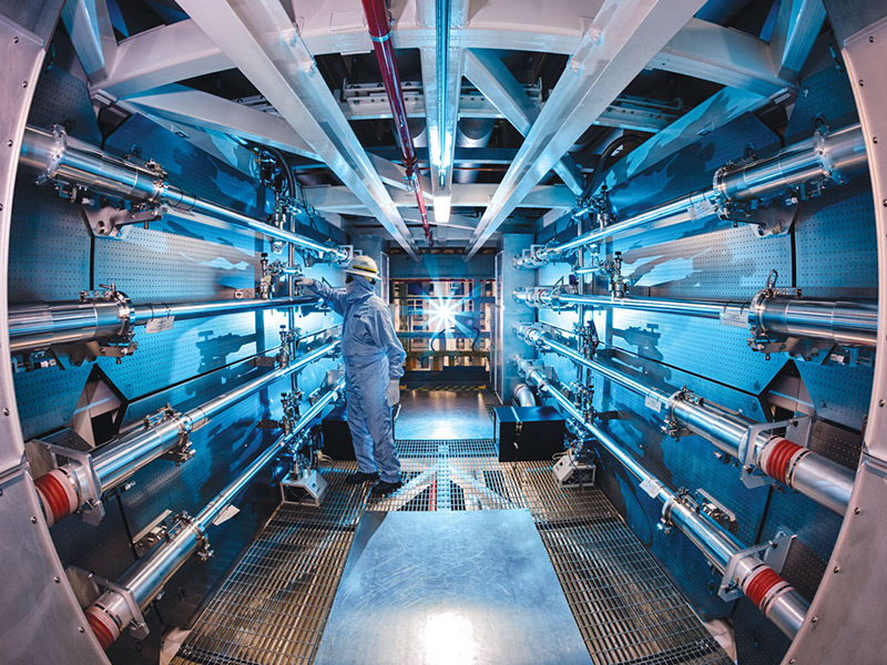 An operator wearing protective clothing, gloves, goggles, and a helmet operating the support structure at the National Ignition Facility.