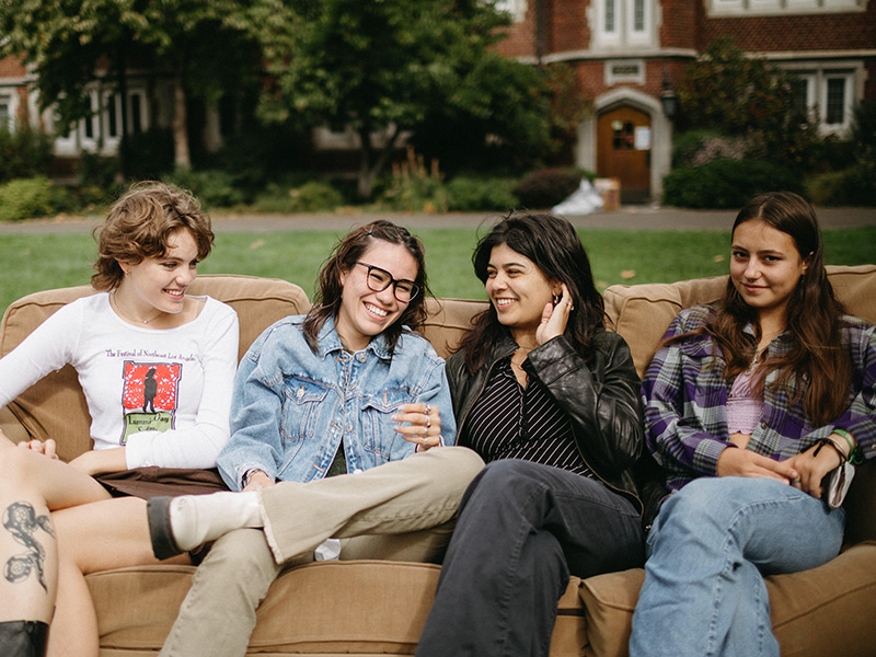 Four Reed students having a fun moment on a sofa in the front lawn.