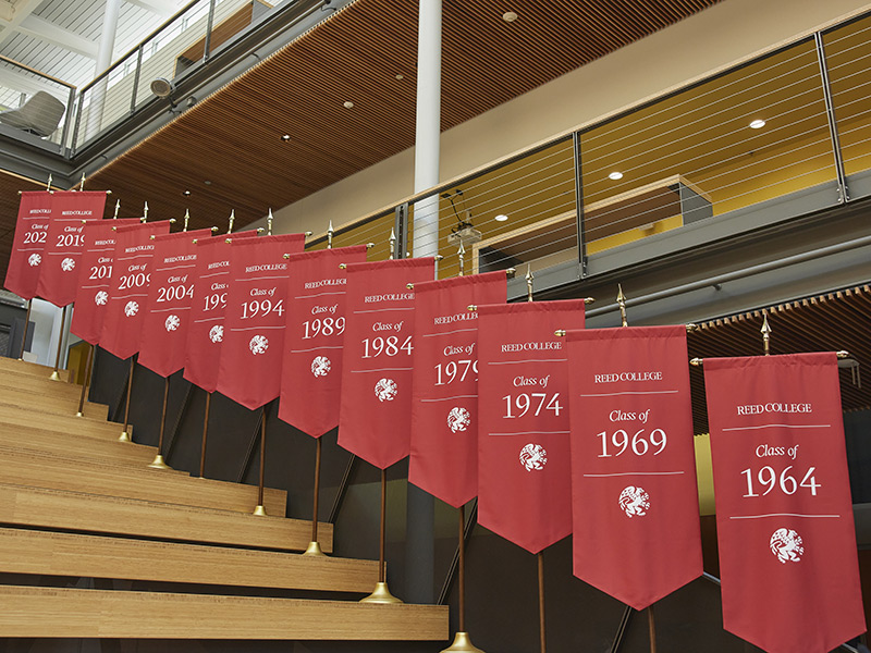 Several graduating class banners on poles lining the steps inside the Performing Arts Building.