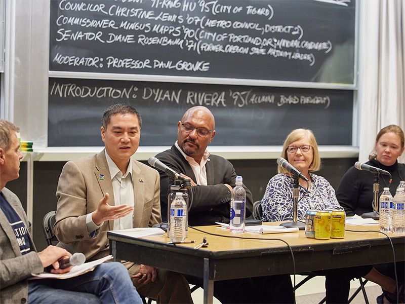 Panelists at a table set with microphones and water bottles.