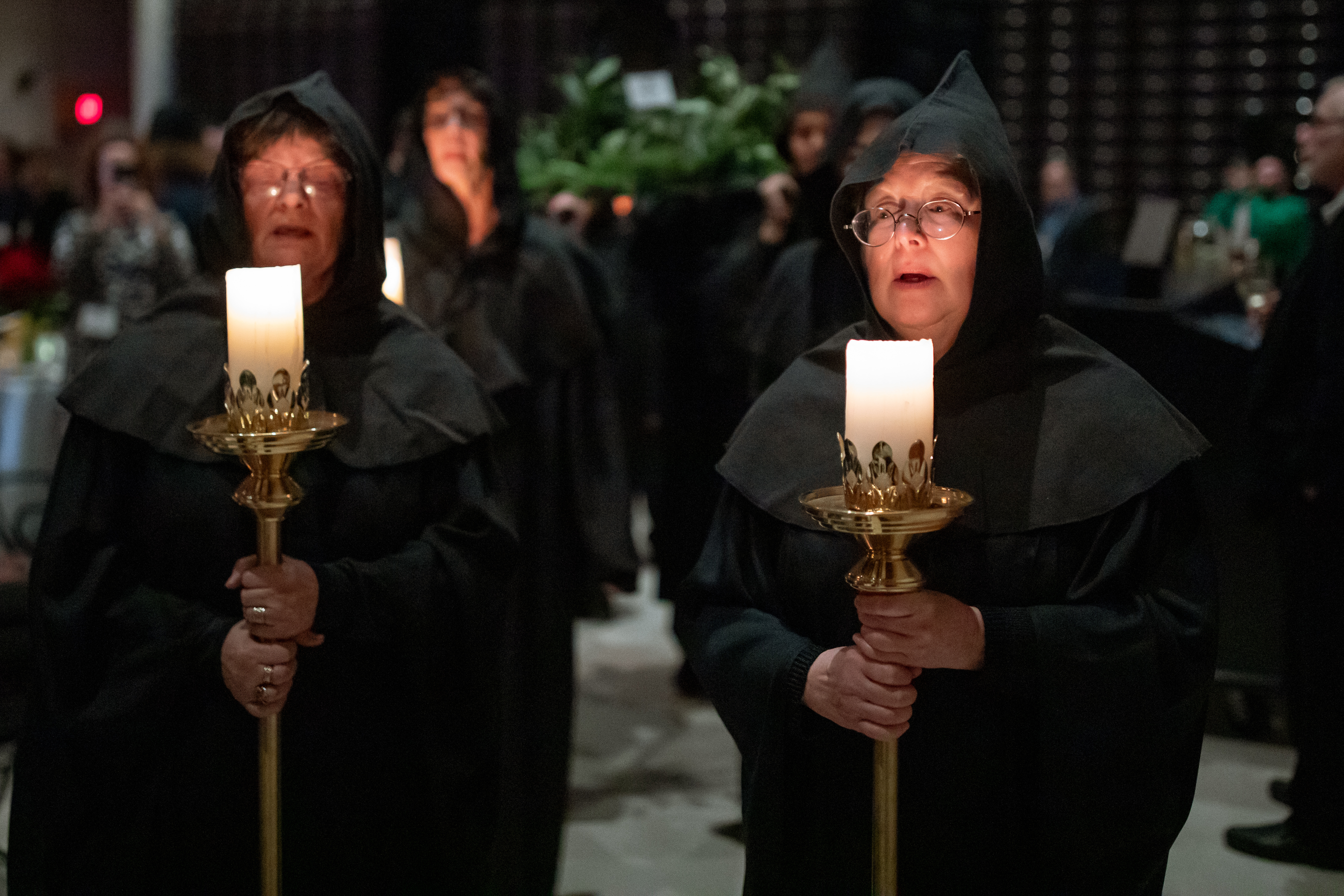 Pair of singers in black robes, holding candles